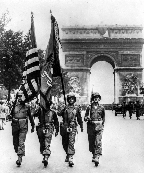 people carrying flags walking down the street in front of a crowd