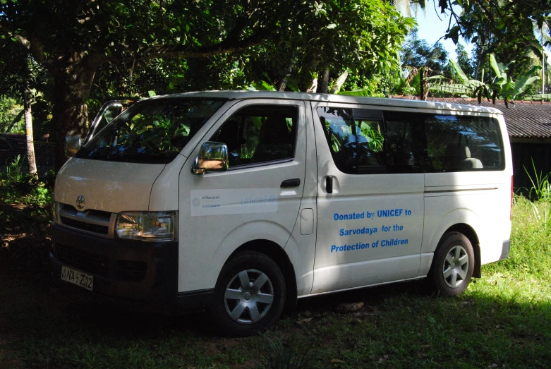 a van parked in the shade on the grass