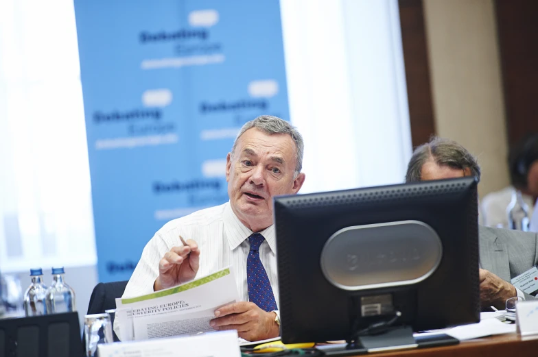 a man is sitting at his desk and is showing off papers