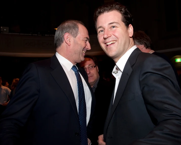 two men dressed up in suits are smiling