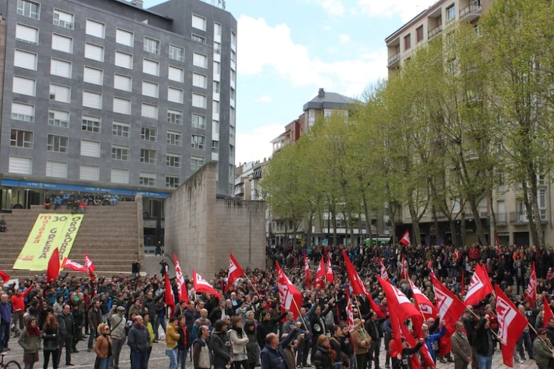 group of people holding red and white flags in a city