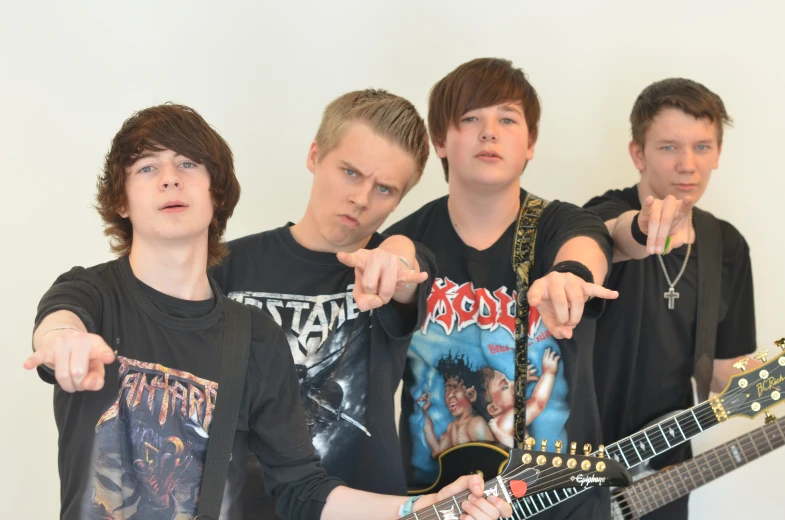 the group of young men in black shirts pose with guitar