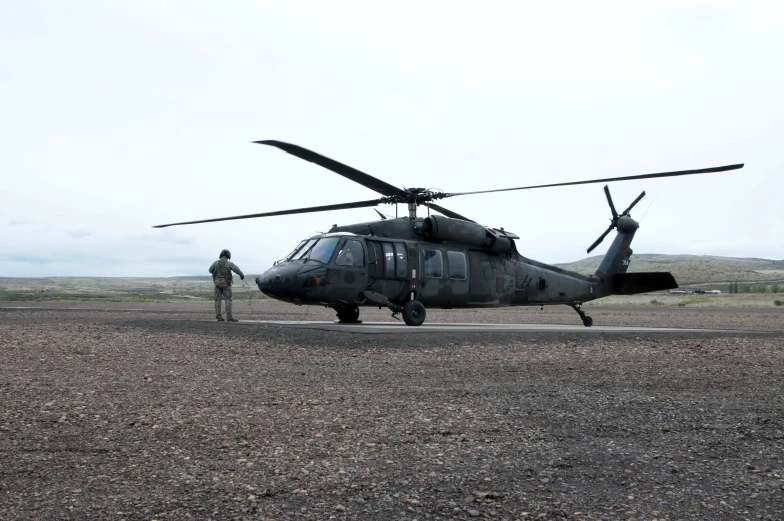 man standing next to black military style helicopter