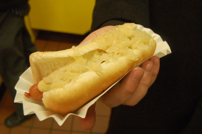 someone holding a foot long  dog in white paper