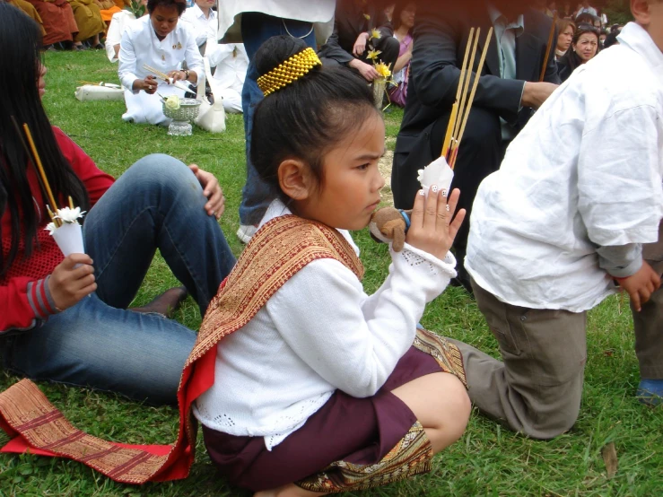 a group of children and adults sitting on the grass