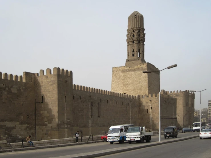 a large wall and a clock tower on the side of a road