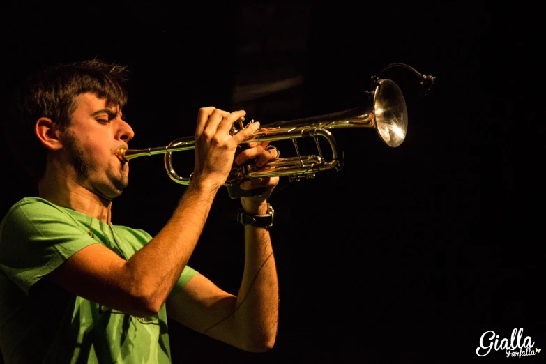 man playing trumpet at night on black background