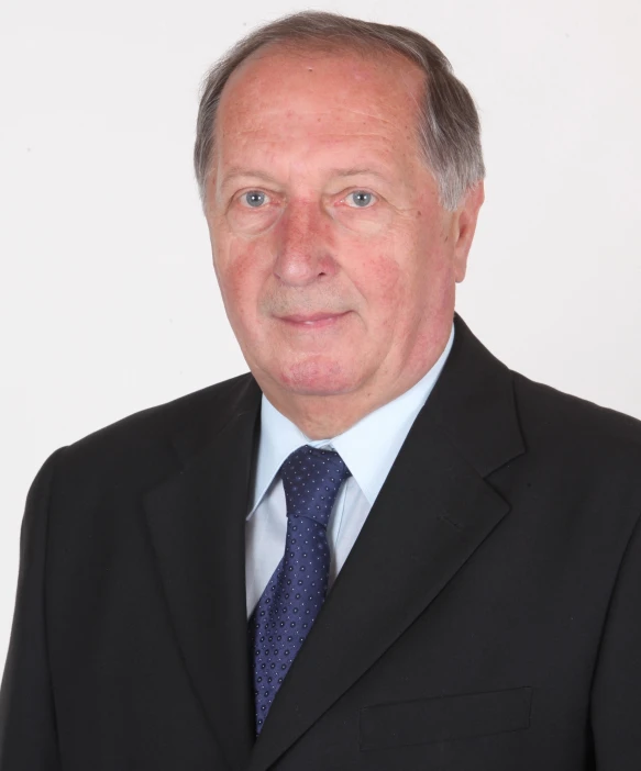 an older man in a black suit and blue tie