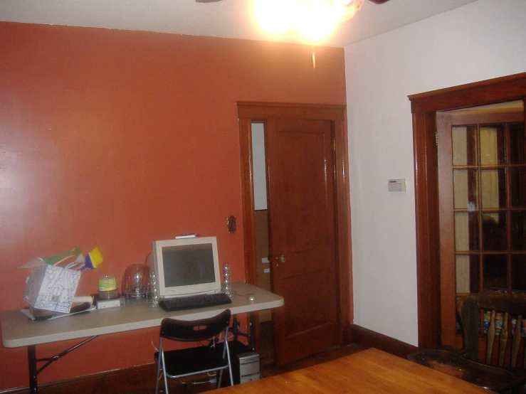 a desk with a monitor and keyboard sits in the corner