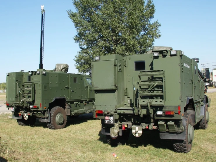 two military vehicles parked side by side on some grass