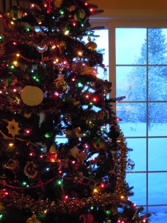 a decorated christmas tree in front of an open window