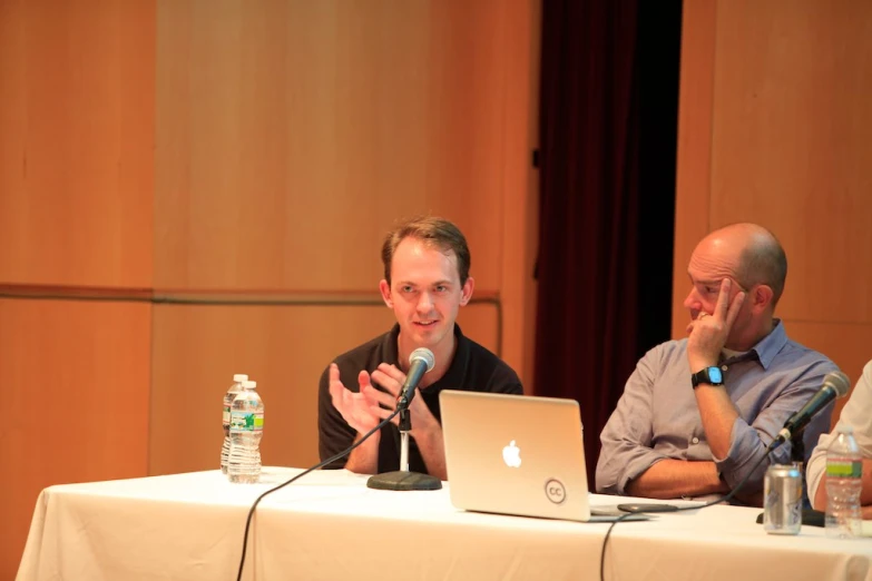 two men at a table speaking and having drinks