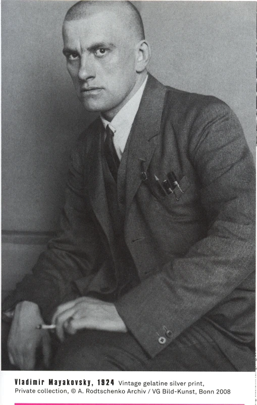 a man in a suit and tie sits with a cigarette