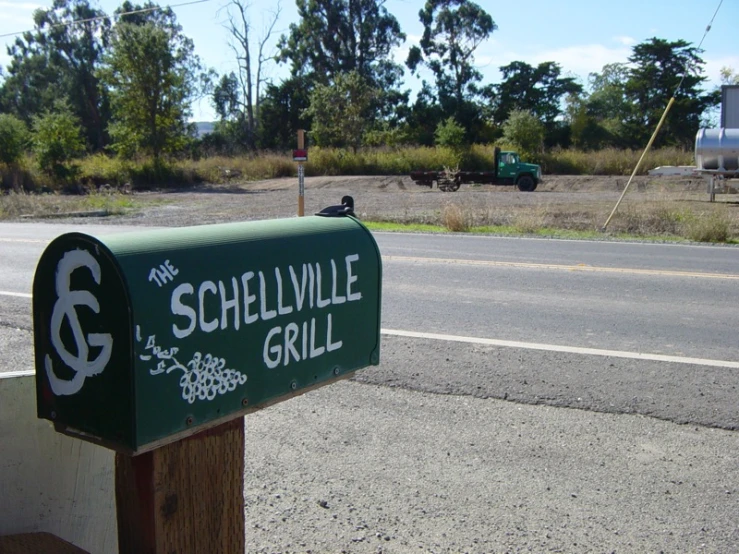 a green street sign in front of a rural road