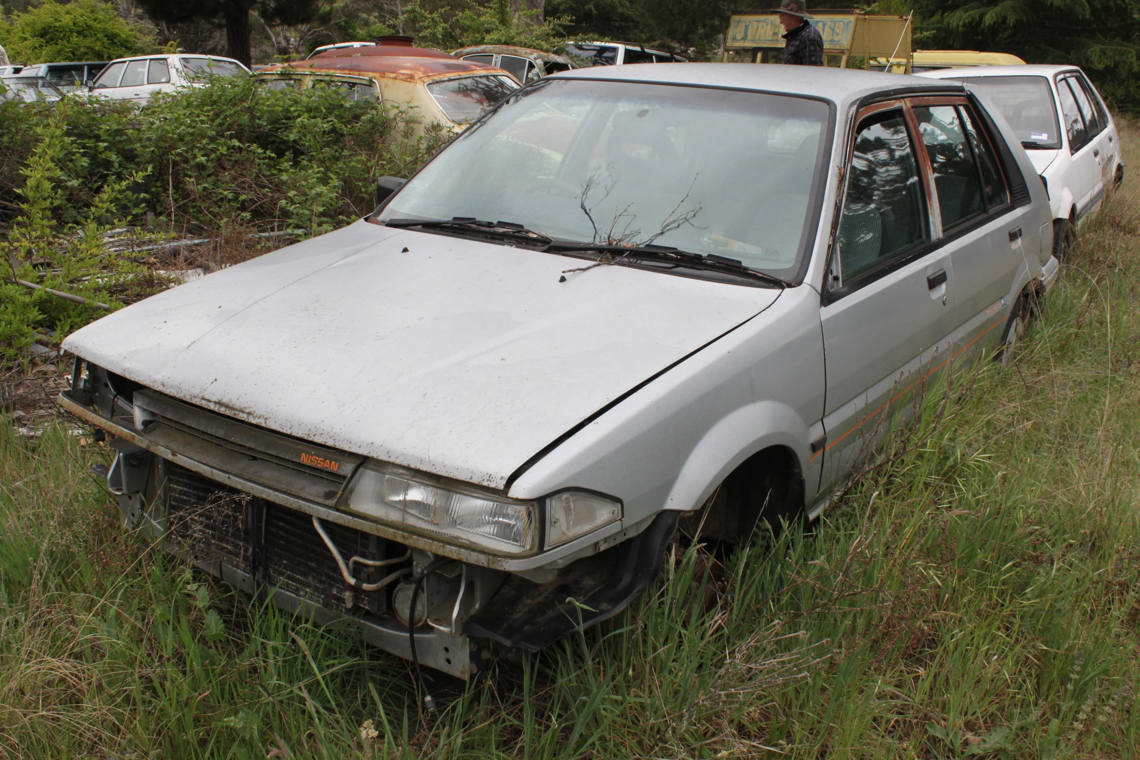 an old car parked on the side of a grass covered road