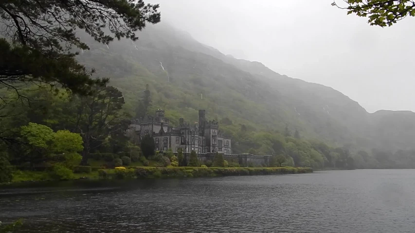 an old mansion on a misty day at the edge of a lake