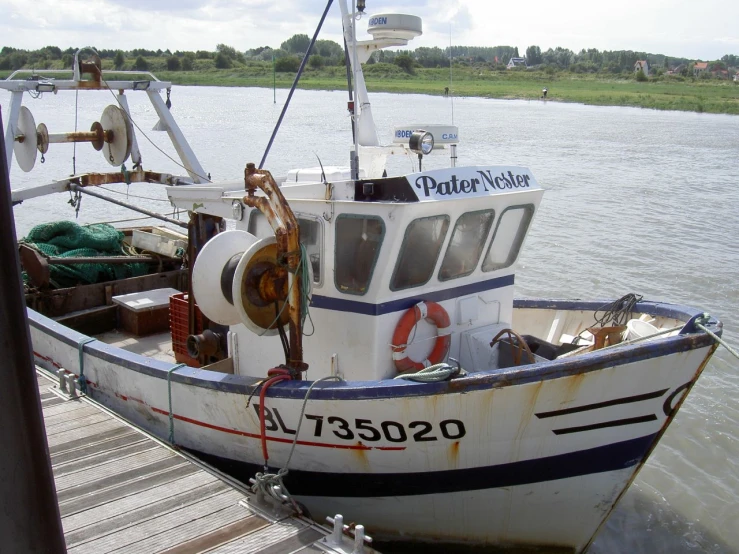 small white boat tied up to dock near water