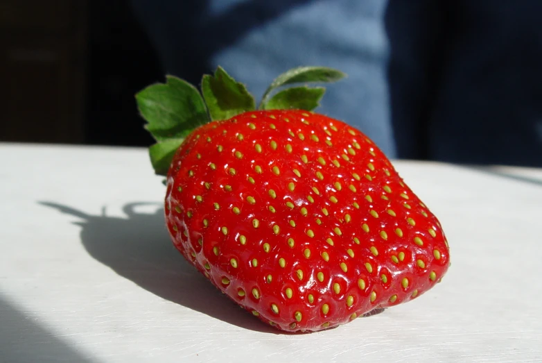 a large red strawberry with green leaves on it