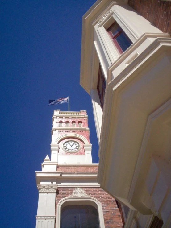 a tall clock tower with a flag hanging from it's side