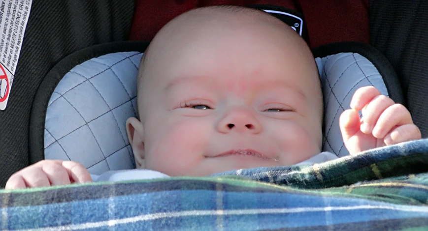 a baby crying and sitting in a car seat