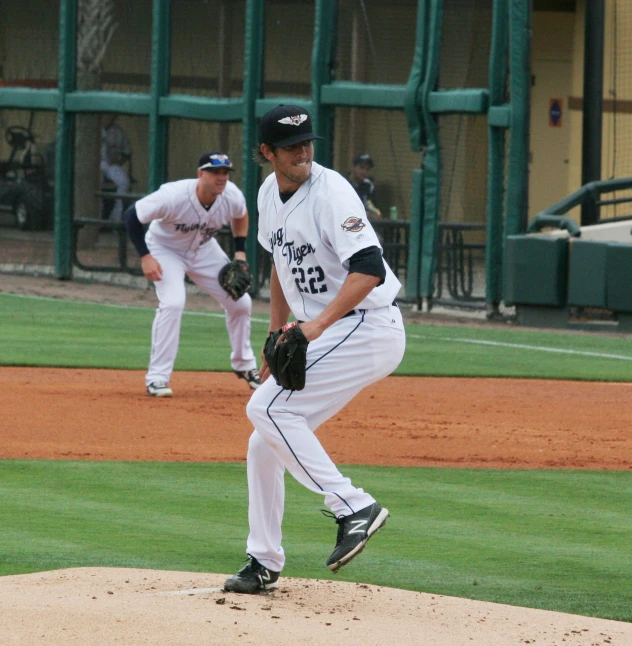 two men in white and black uniforms on a field playing baseball