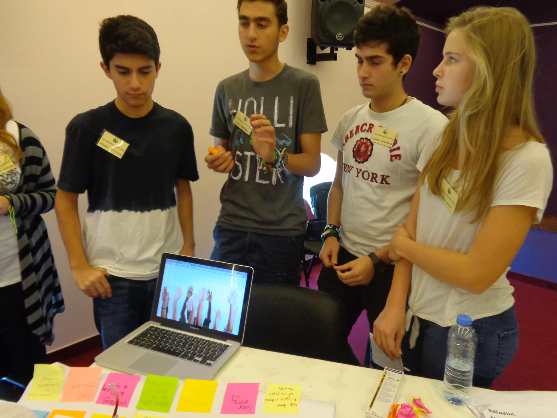 several people standing around a table with a laptop on it