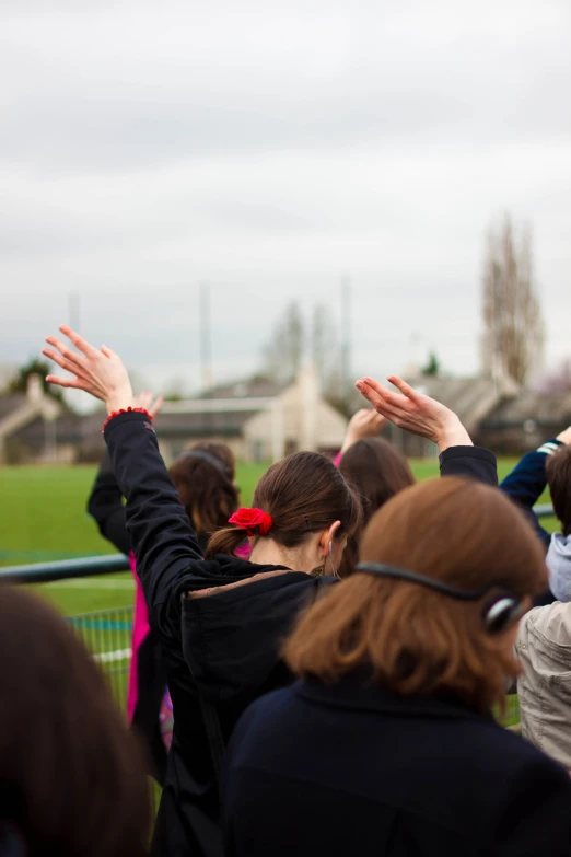 several people at an outside event are holding their arms up to the sky