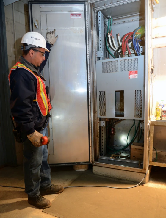 an electrician stands beside the large electrical cabinet