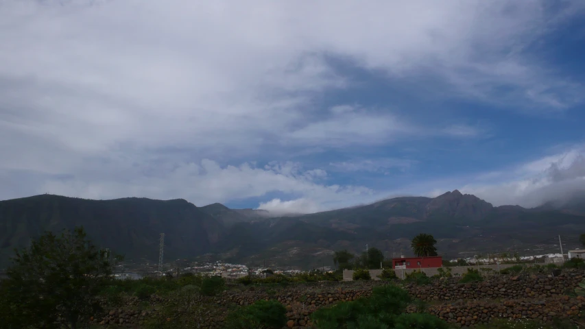 a mountain view with some trees, bushes, and buildings