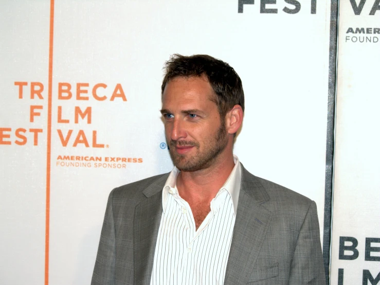 a man wearing a suit standing in front of a white wall