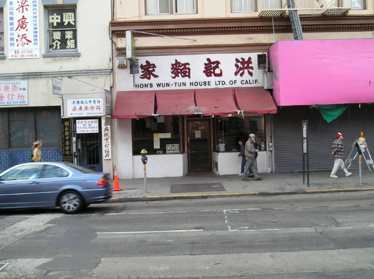 some cars are driving down a street past shops