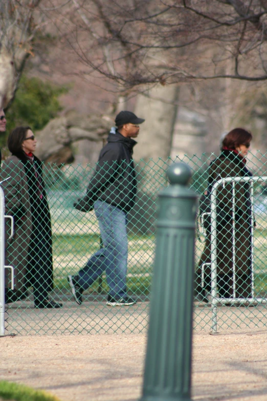 people are walking past a metal gate and fence