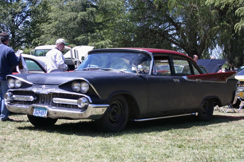 a vintage car parked on the grass near some other antique cars