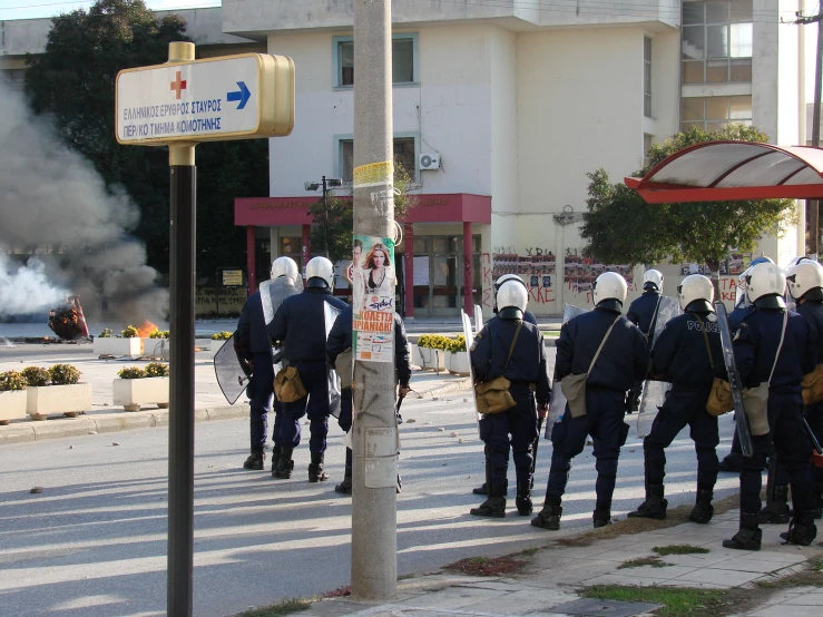 policemen standing on the side of the road with smoke coming from behind