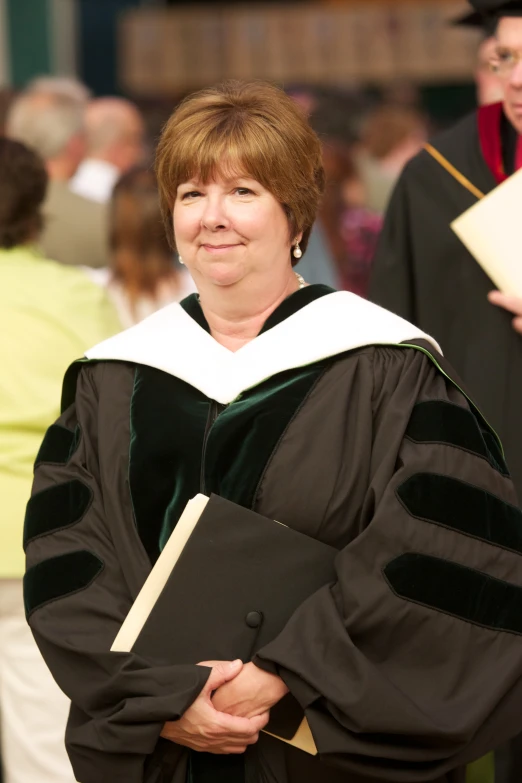 a woman with brown hair in a robe and graduation cap