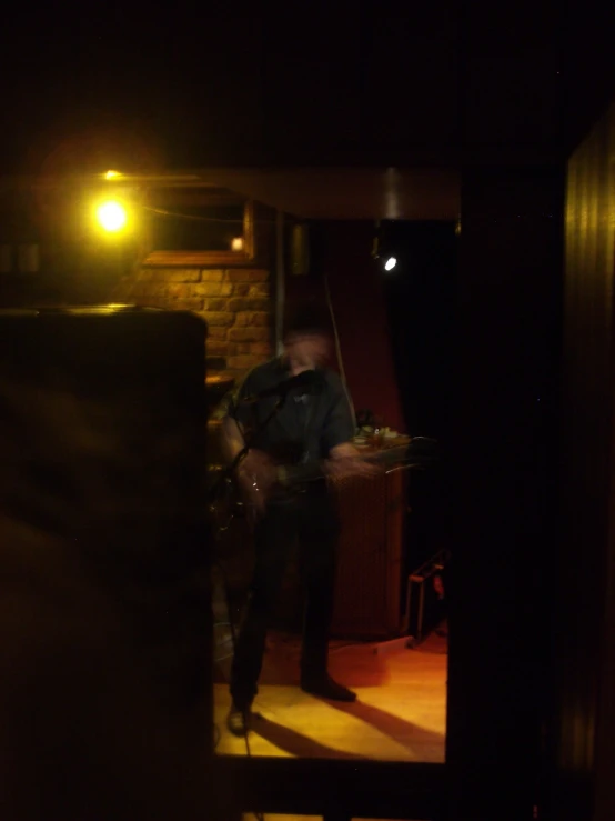 a man holding a guitar in the dark