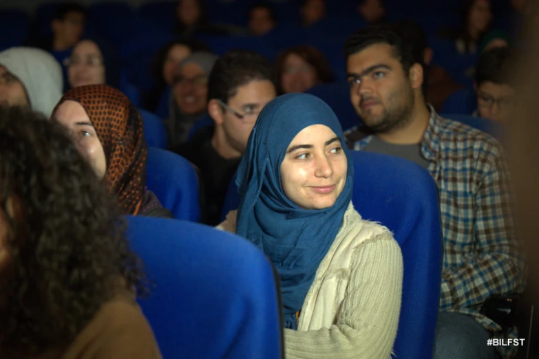 woman in a blue scarf looking up in a crowd