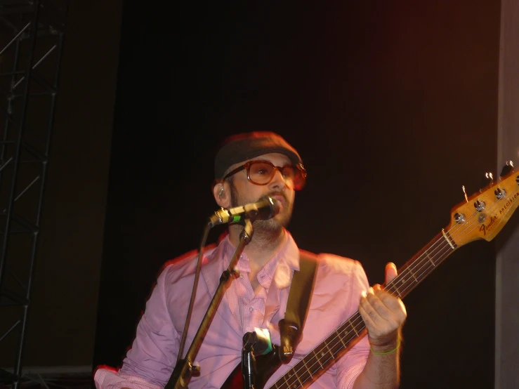 a man wearing glasses and holding an electric guitar