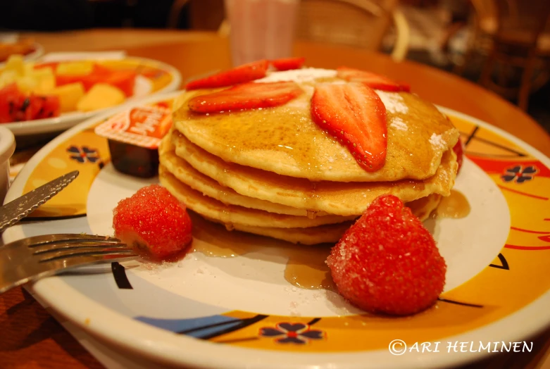 a plate topped with pancakes covered in syrup and sliced strawberries