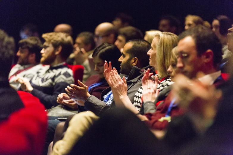 a group of people at a public meeting clapping and clapping their hands