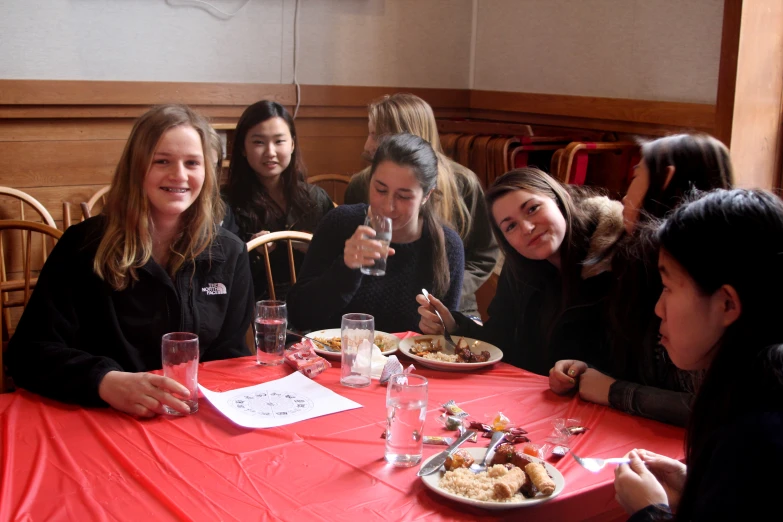 a group of women sitting around a table having a meal