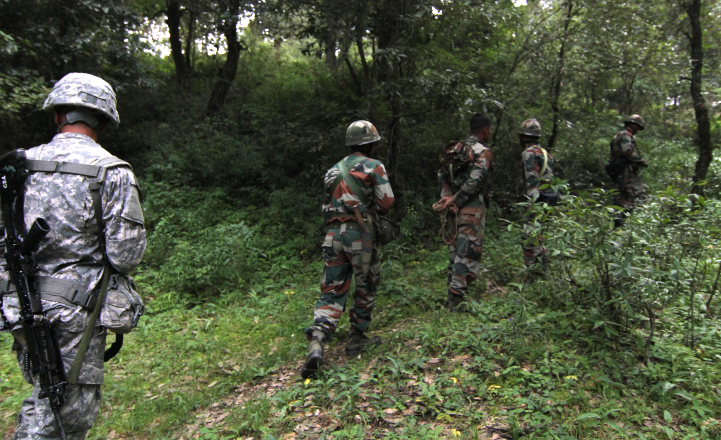 soldiers in camouflage standing on the trail looking down