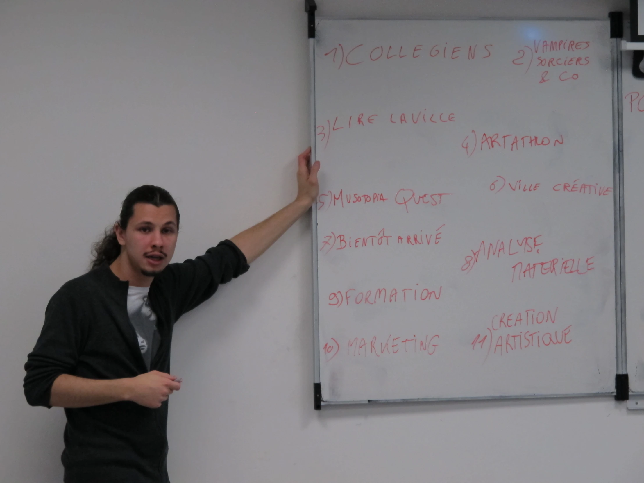 a man writing on a white board next to a blackboard