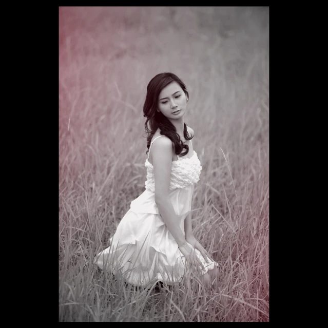 an asian woman in a white dress sitting on tall grass