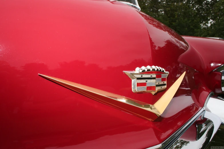 the tail end of a red car with gold emblem