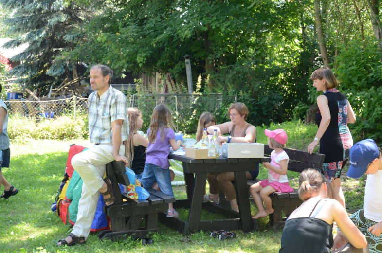 a family gathers around a picnic table to eat