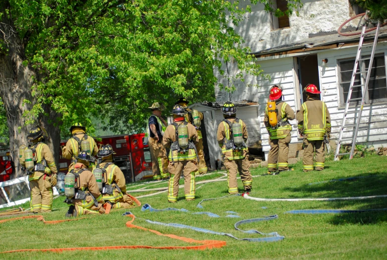 a group of fire fighters standing around in front of a house