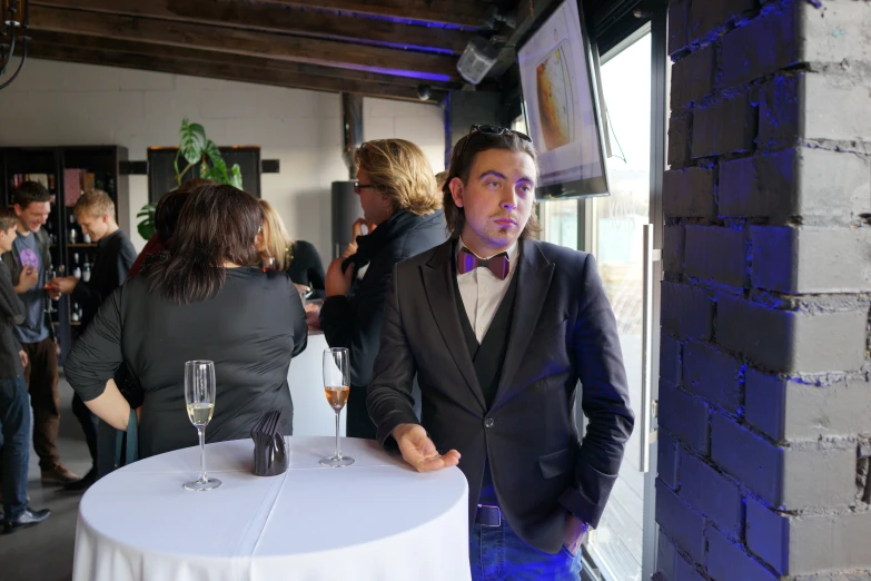 man in a tuxedo standing at a round white table