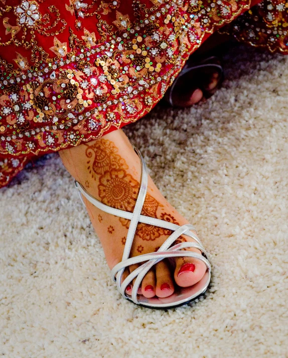 a woman with henna on her feet standing in the middle of carpet