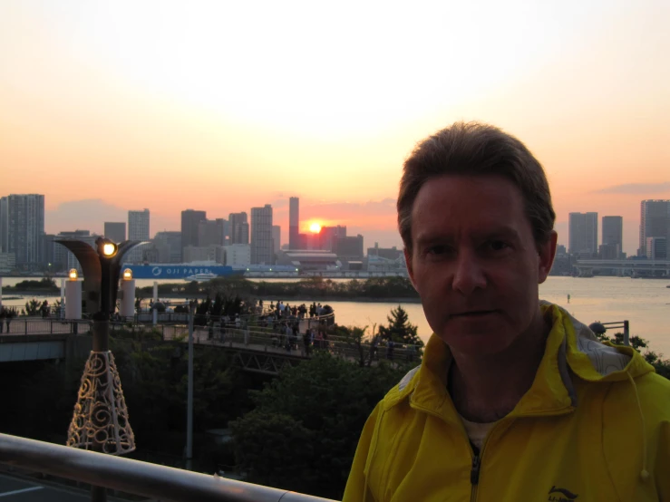 a man posing for the camera on a railing by the water